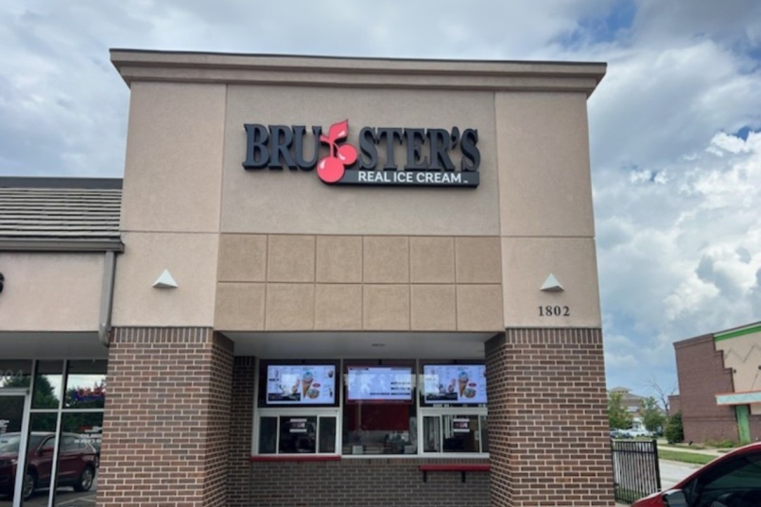exterior of a building with walk up windows and a sign that says brusters real ice cream with a cherry in the middle of brusters